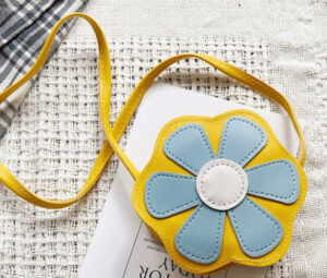 桌子上放著一個黃色和藍色花朵斜背包。